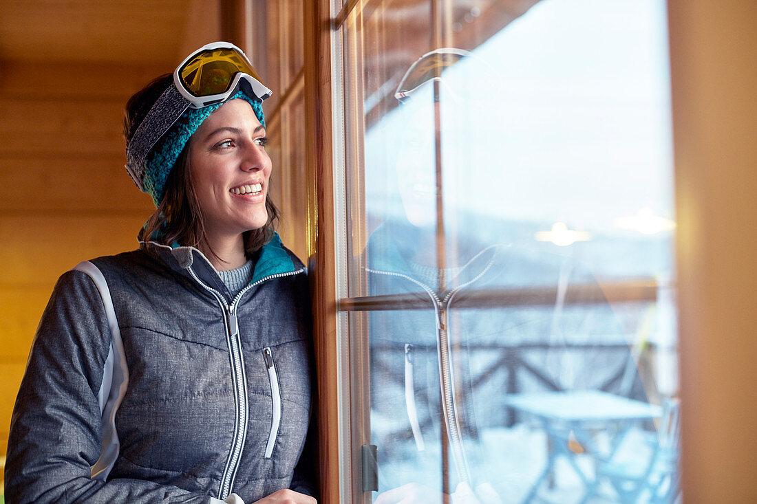 Smiling female skier looking out cabin window