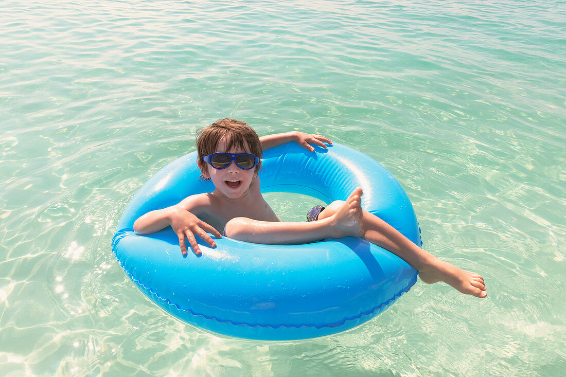 Boy in sunglasses floating in inflatable ring