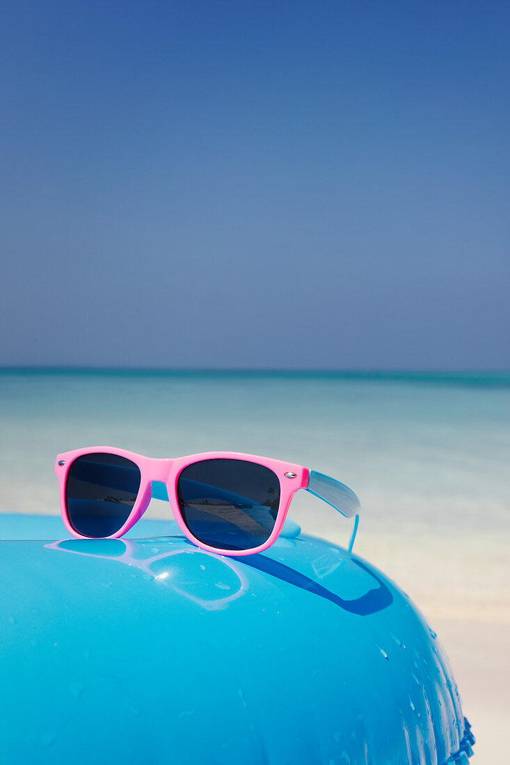 Pink sunglasses on inflatable ring on ocean