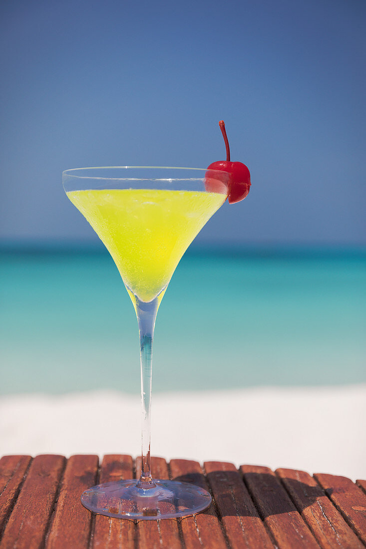 Yellow cocktail with cherry on ocean beach