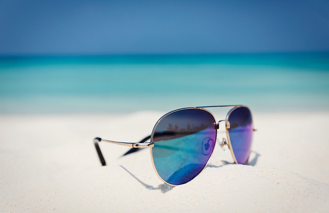 Close up aviator sunglasses in sand on ocean beach