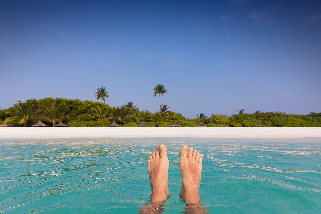 Barefoot man floating with beach view