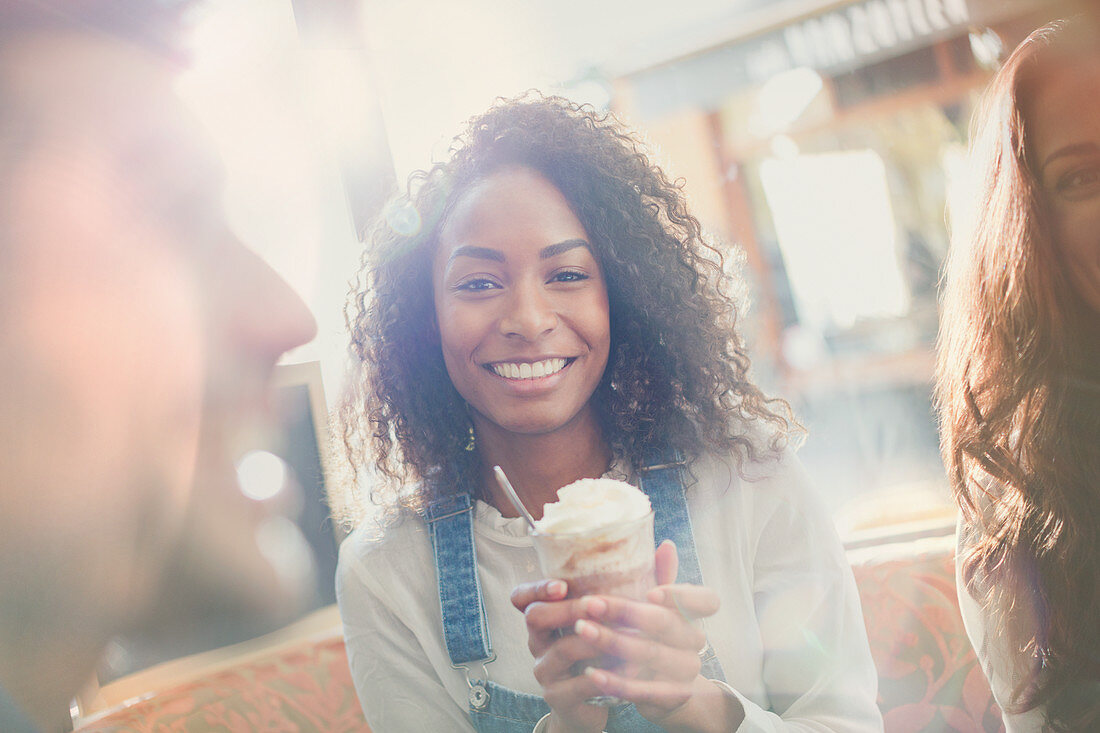 Young woman drinking milkshake with friends