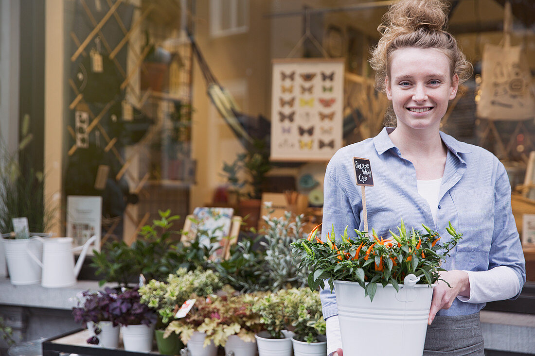 Smiling female florist with potted plant