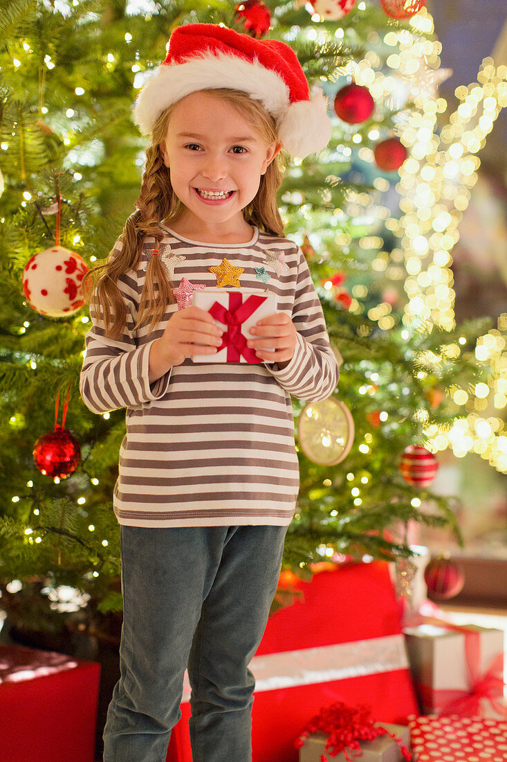 Smiling girl in Santa hat holding gift