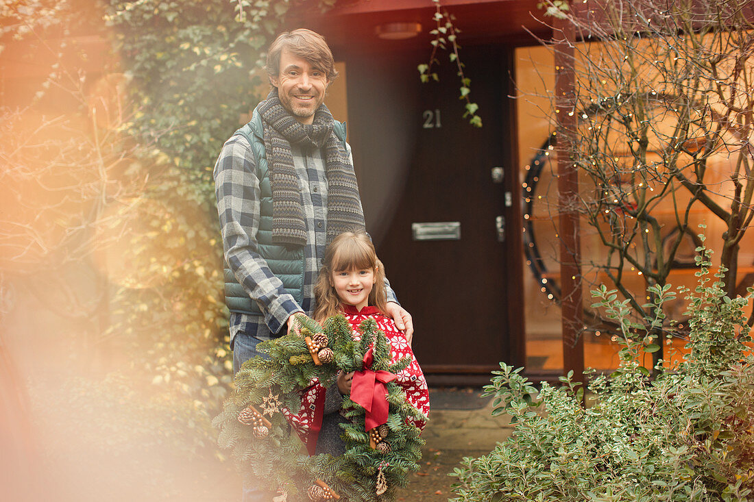 Father and daughter holding Christmas wreath