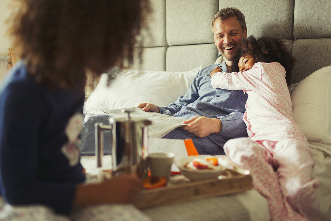 Daughter hugging father reading newspaper