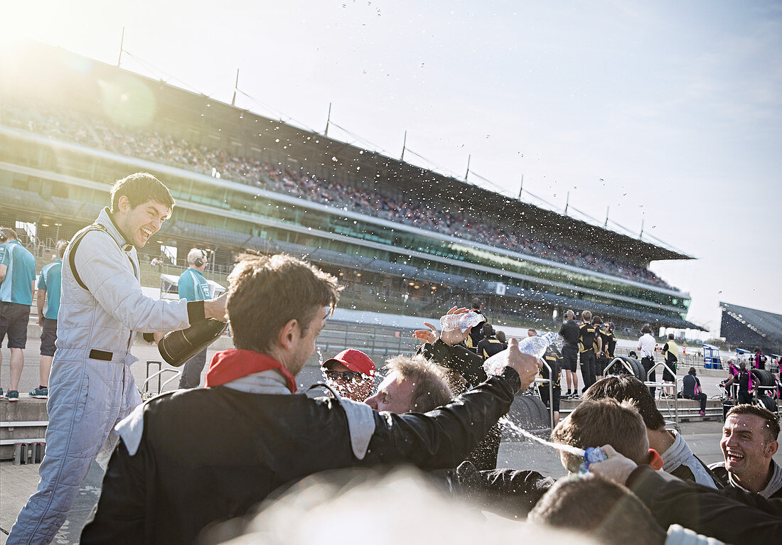 Racing team and driver spraying champagne