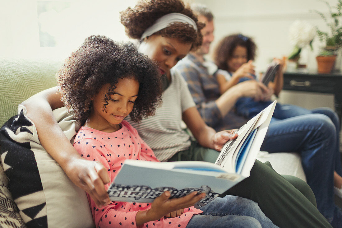 Parents reading books with daughters