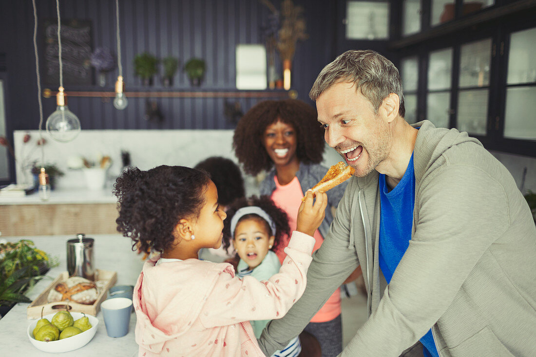 Multi-ethnic daughter feeding toast to father