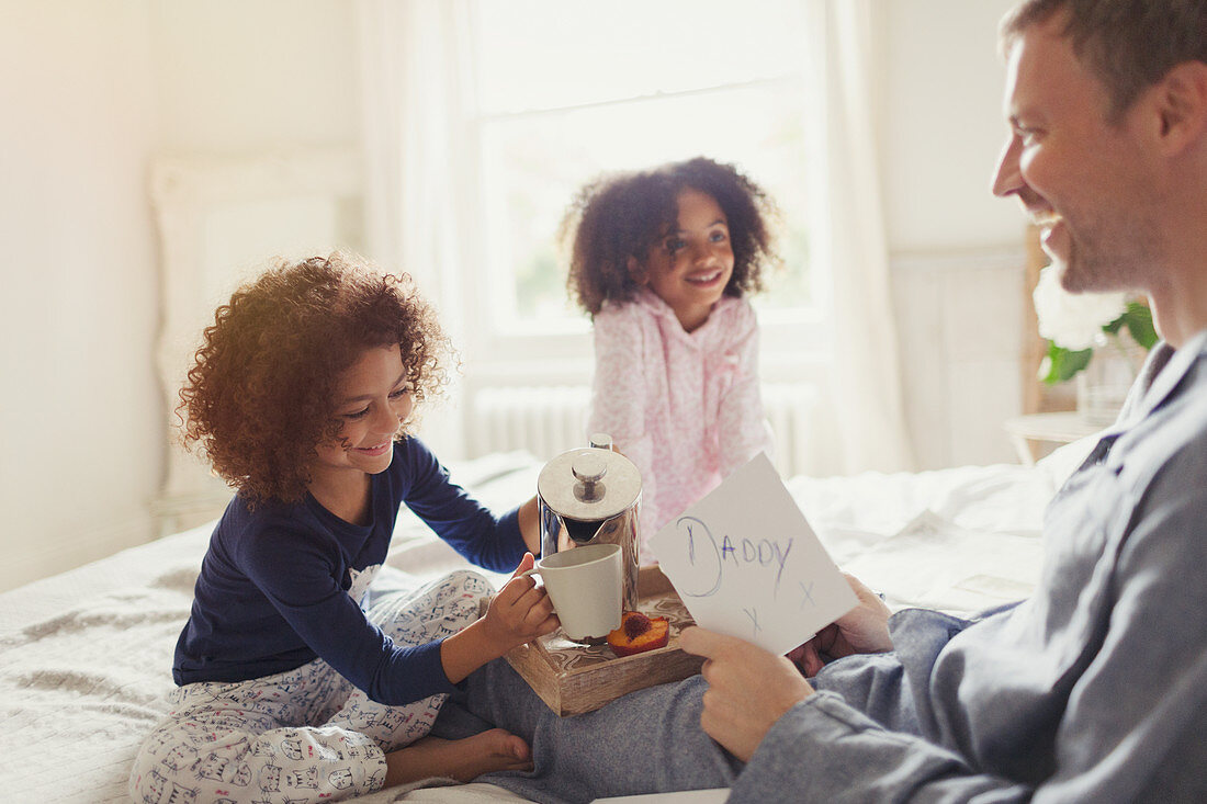 Daughters serving coffee to father on Father's Day