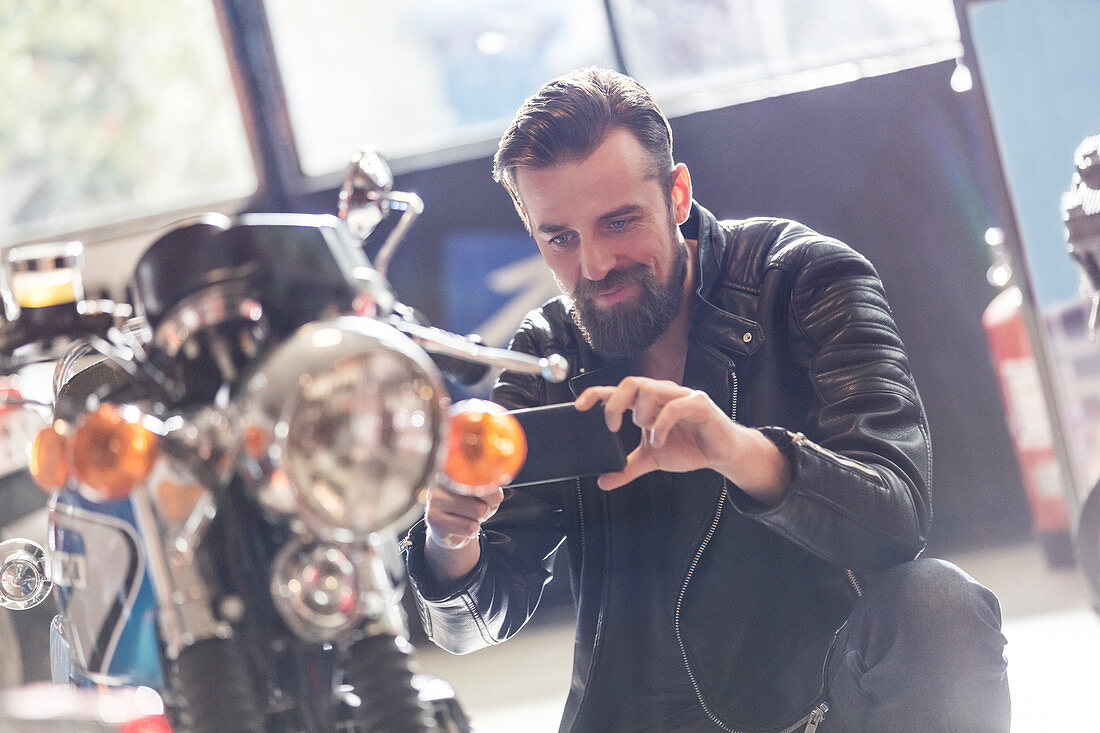 Man photographing motorcycle in shop