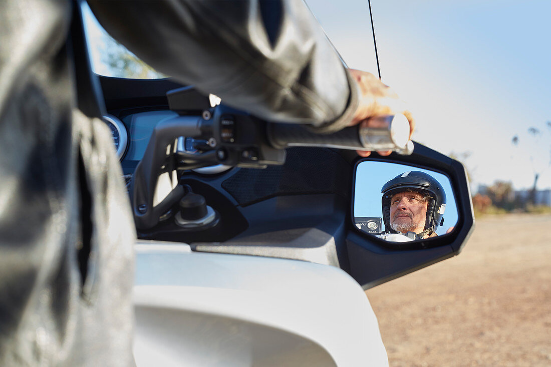 Senior man in side-view mirror riding motorcycle