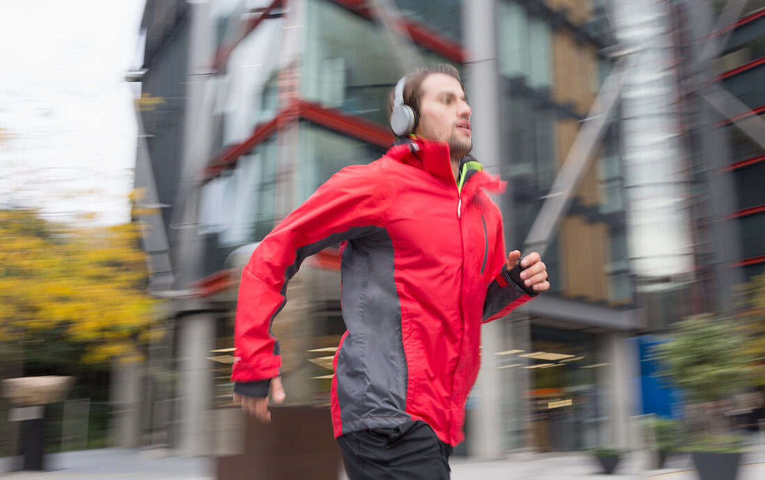 Man running with headphones past building