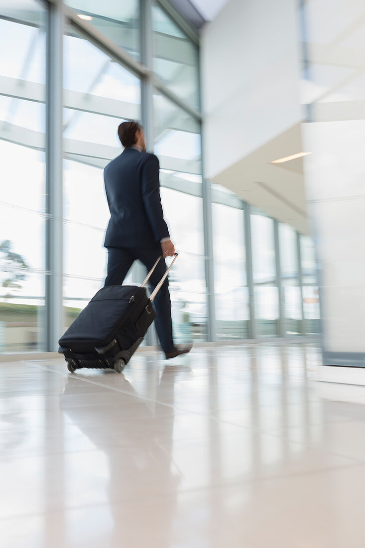 Businessman walking, pulling suitcase in airport