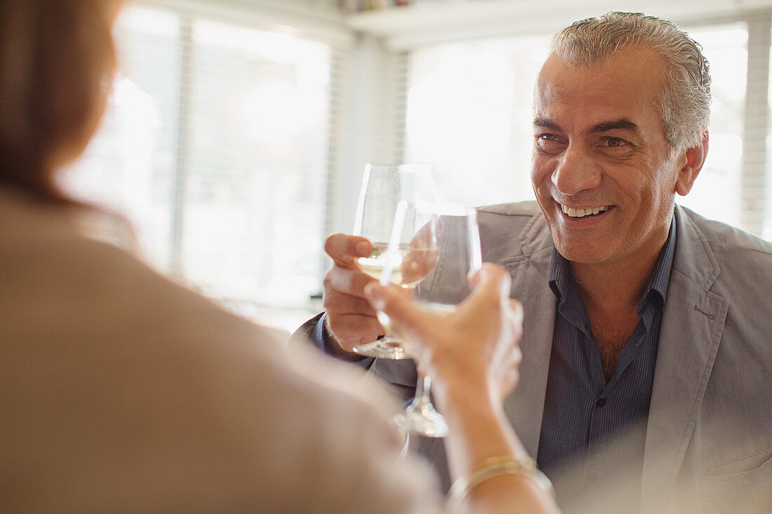 Senior man toasting wine glasses with woman