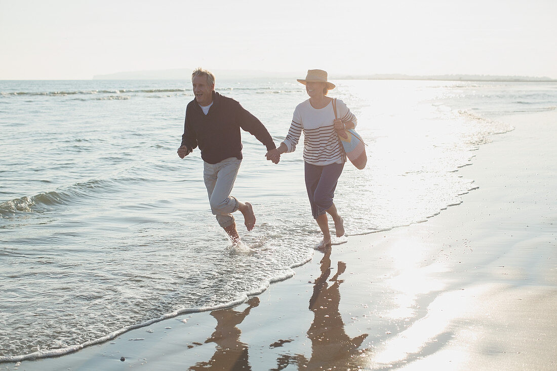 Playful mature couple holding hands and running