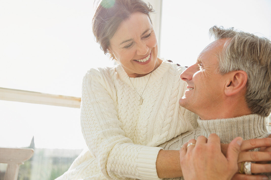 Affectionate mature couple hugging on sunny porch