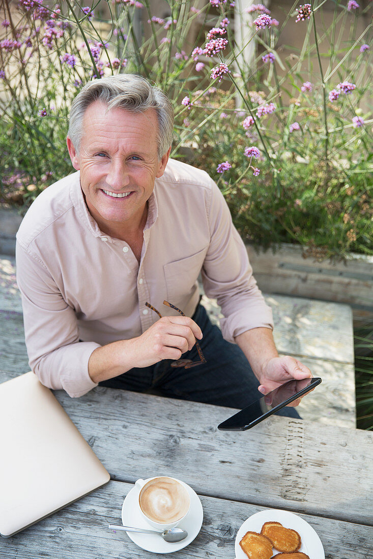 Senior man using tablet and drinking coffee