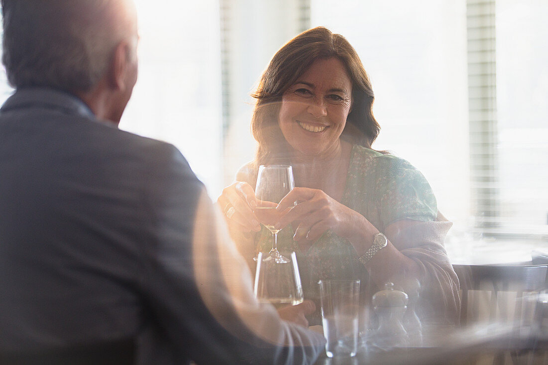 Smiling mature couple drinking wine, dining table
