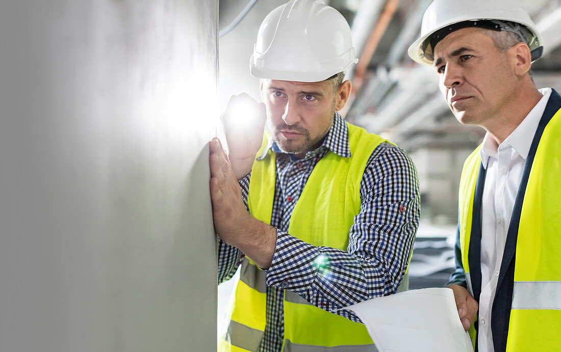 Male engineer with flashlight examining wall