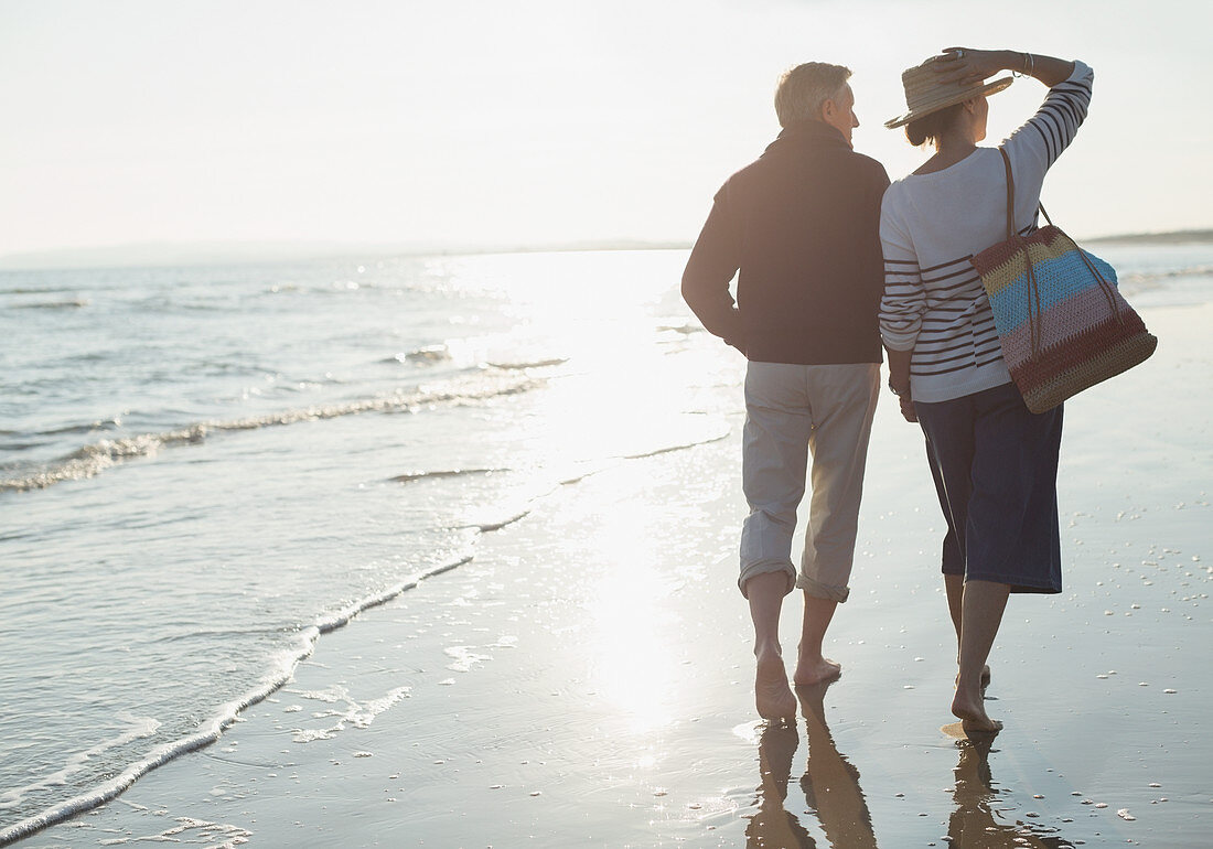 Mature couple walking on sunny ocean beach