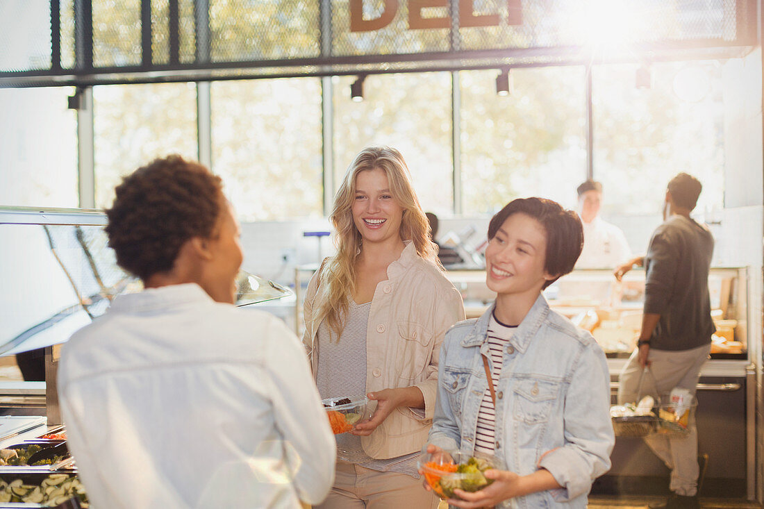 Young women friends at salad bar in market