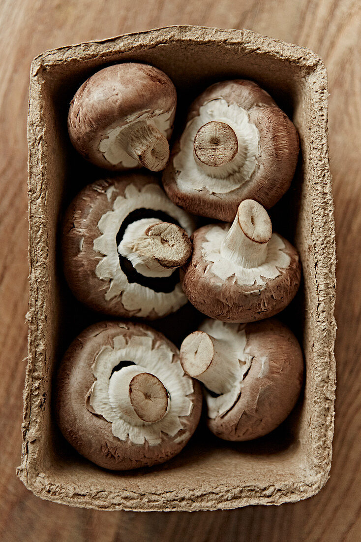 Fresh, six brown mushrooms in container