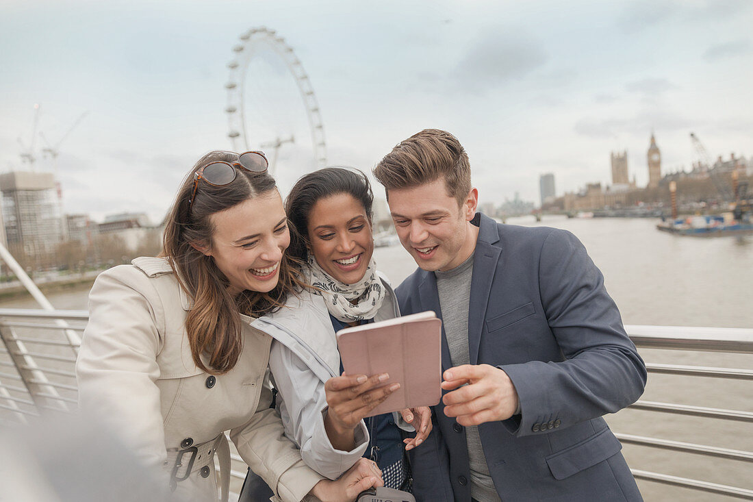 Friend tourists using tablet, London, UK