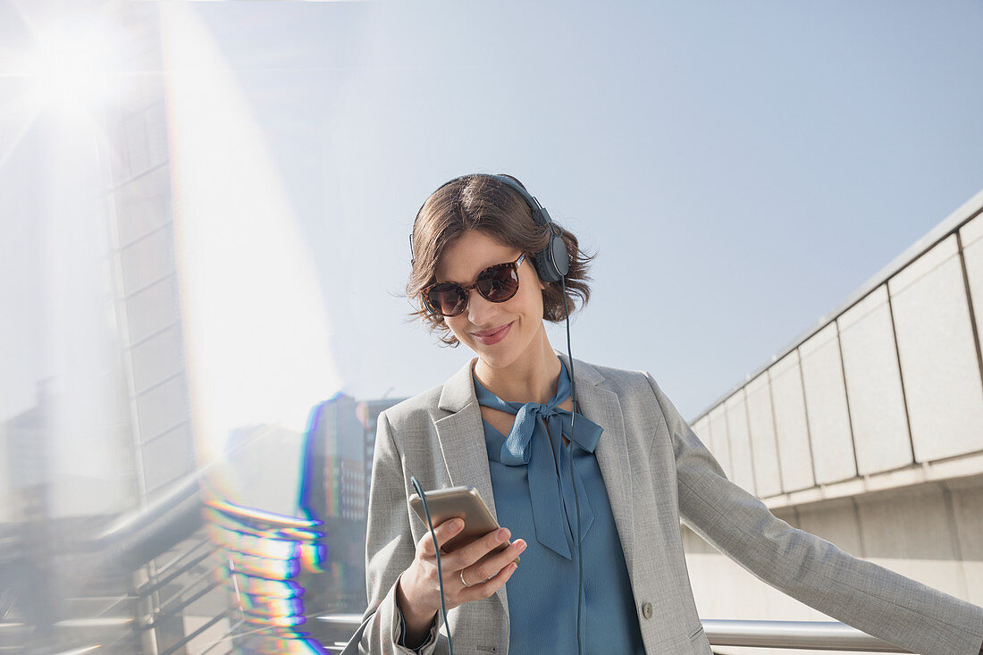 Businesswoman with sunglasses listening to music