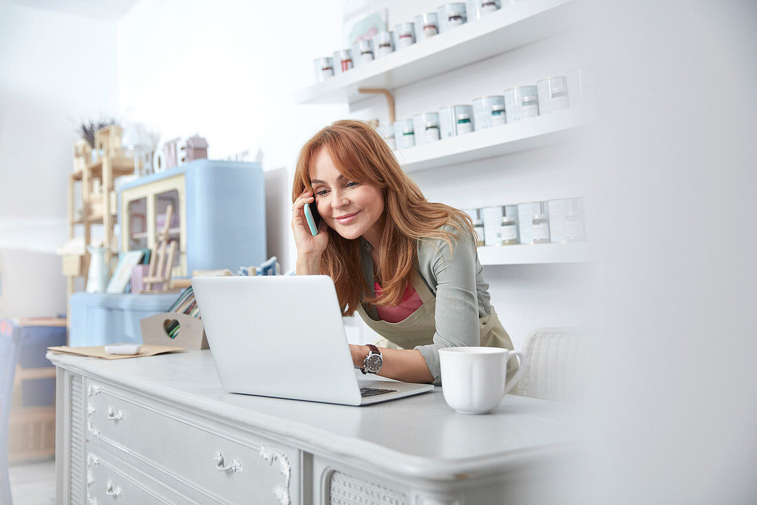 Smiling business owner using laptop at counter