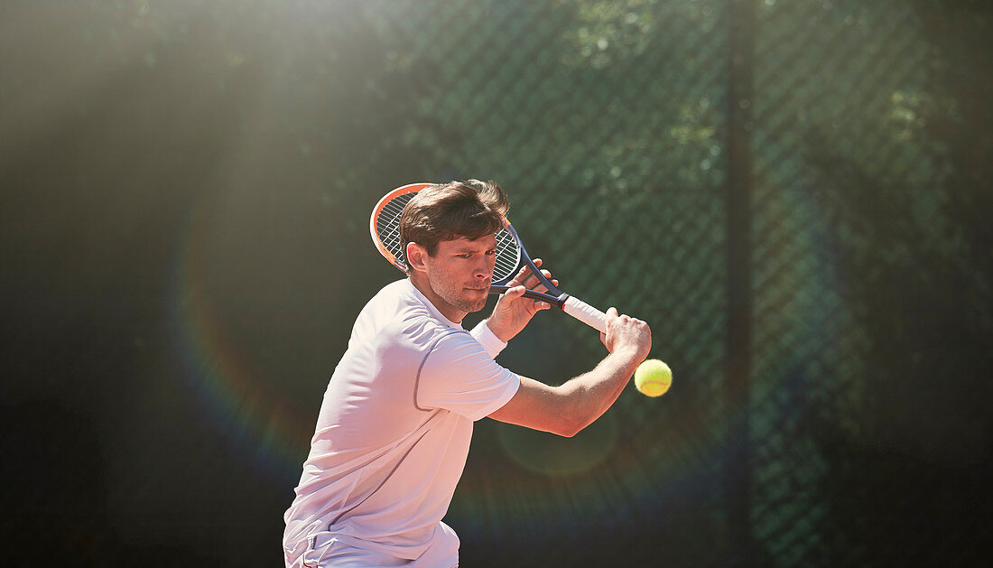 Young man playing tennis, swinging tennis racket