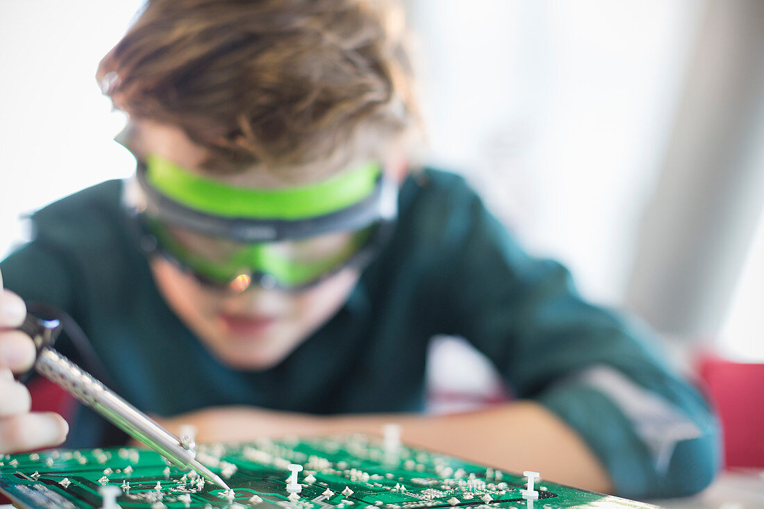 Focused boy student soldering circuit board