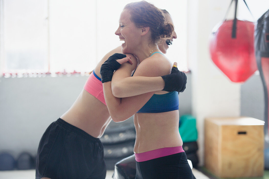 Smiling female boxers hugging in gym