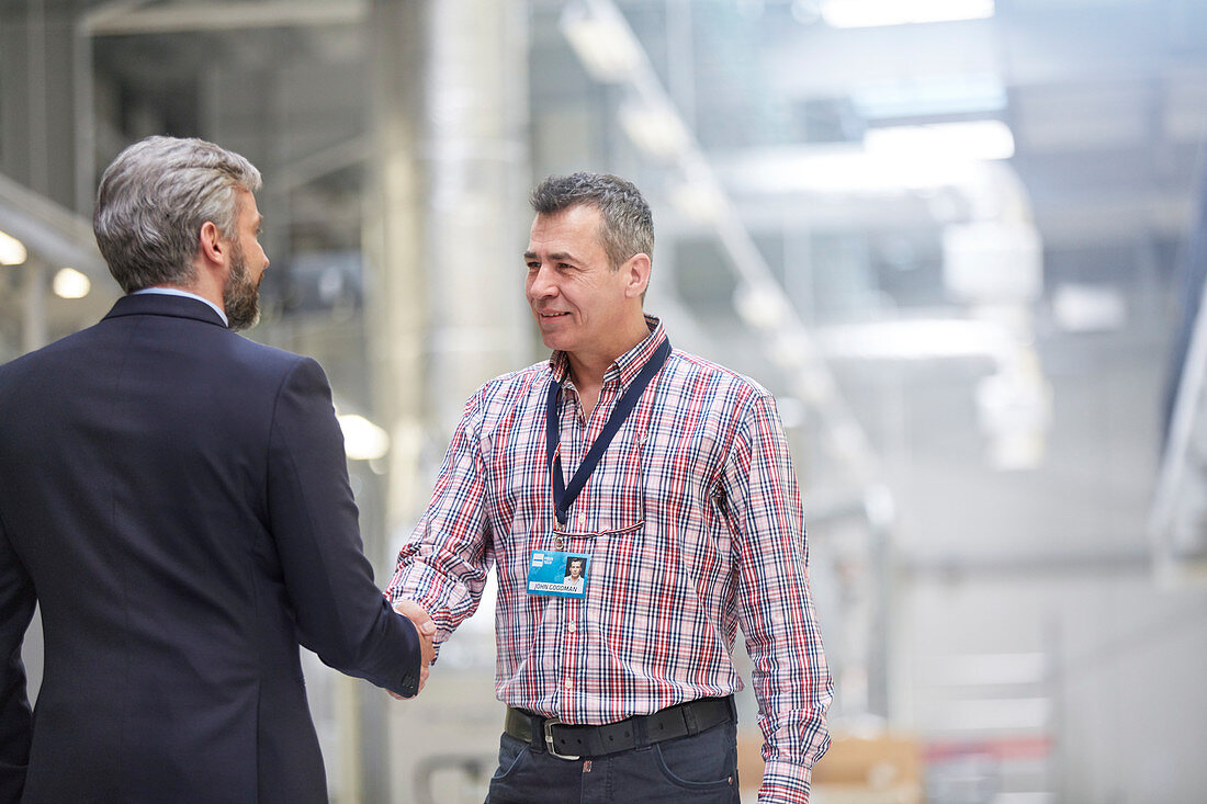 Businessman and supervisor handshaking in factory