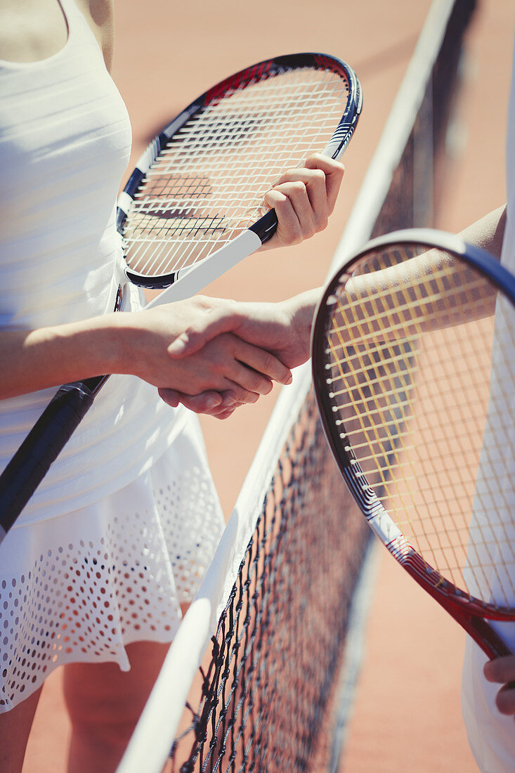 Tennis players handshaking in sportsmanship at net