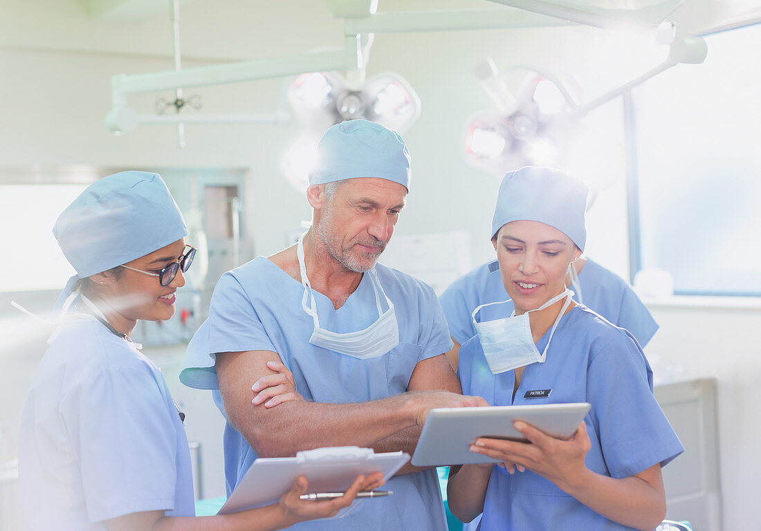 Surgeons and nurse using digital tablet