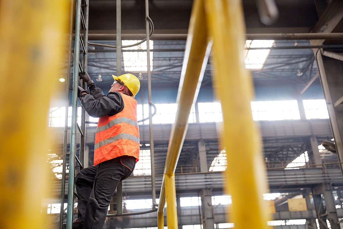 Male worker climbing ladder in factory