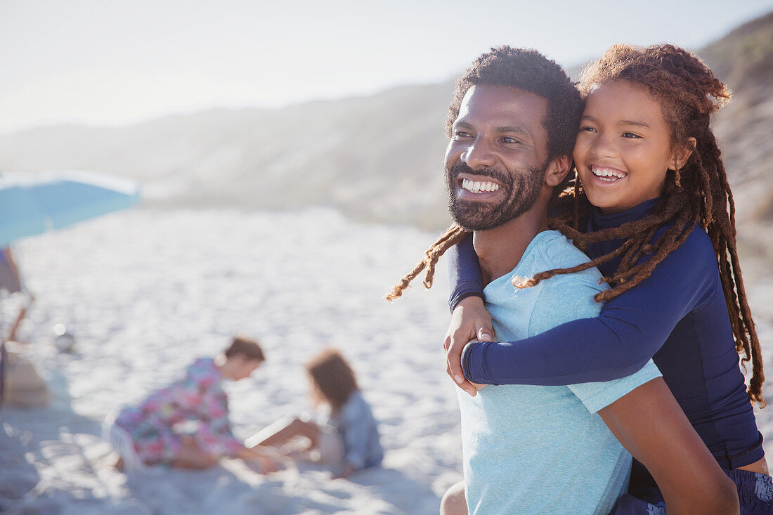 Smiling, father piggybacking daughter