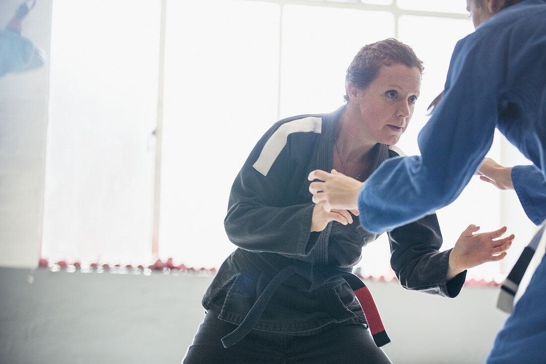 Determined, tough woman practicing jiu-jitsu in gym