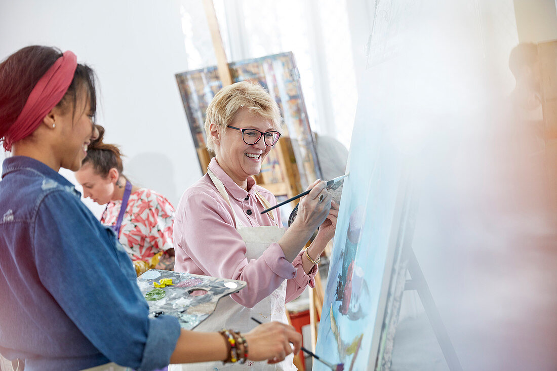 Female artists painting in art class studio
