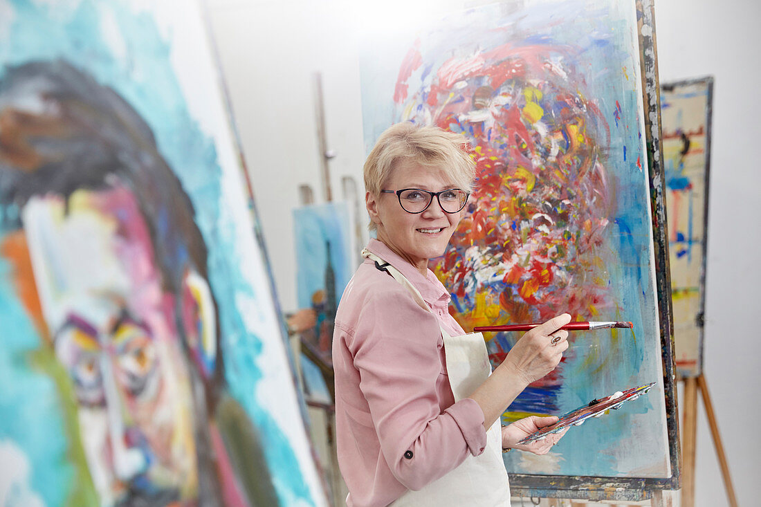 Portrait female artist painting at canvas