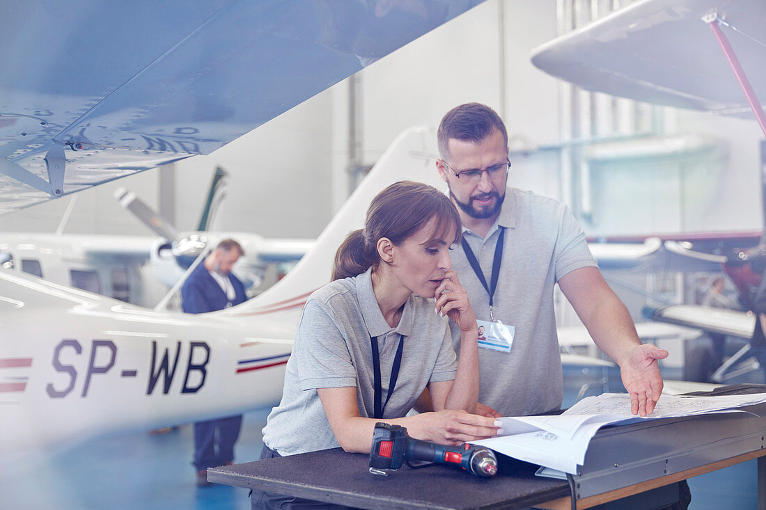 Airplane mechanics reviewing plans in hangar