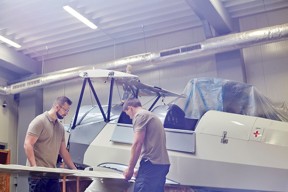 Male engineers assembling airplane in hangar