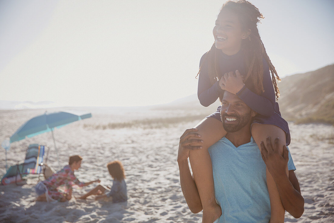 Smiling father carrying daughter on shoulders