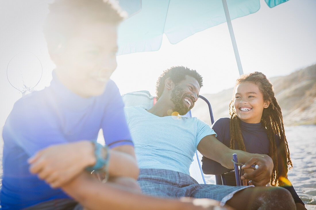 Father and children relaxing on sunny summer beach