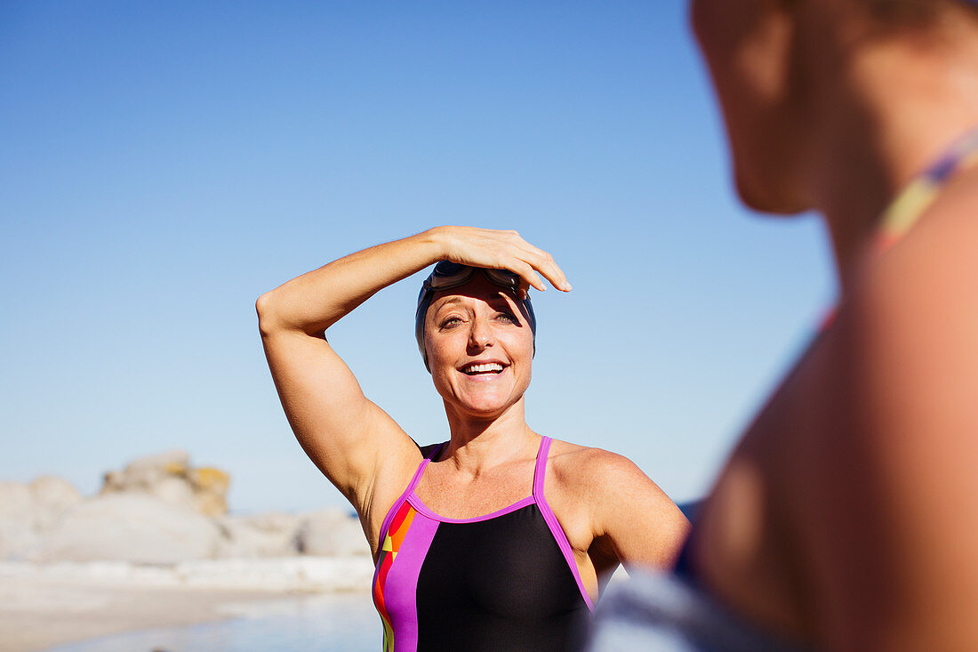 Smiling female swimmers on sunny beach