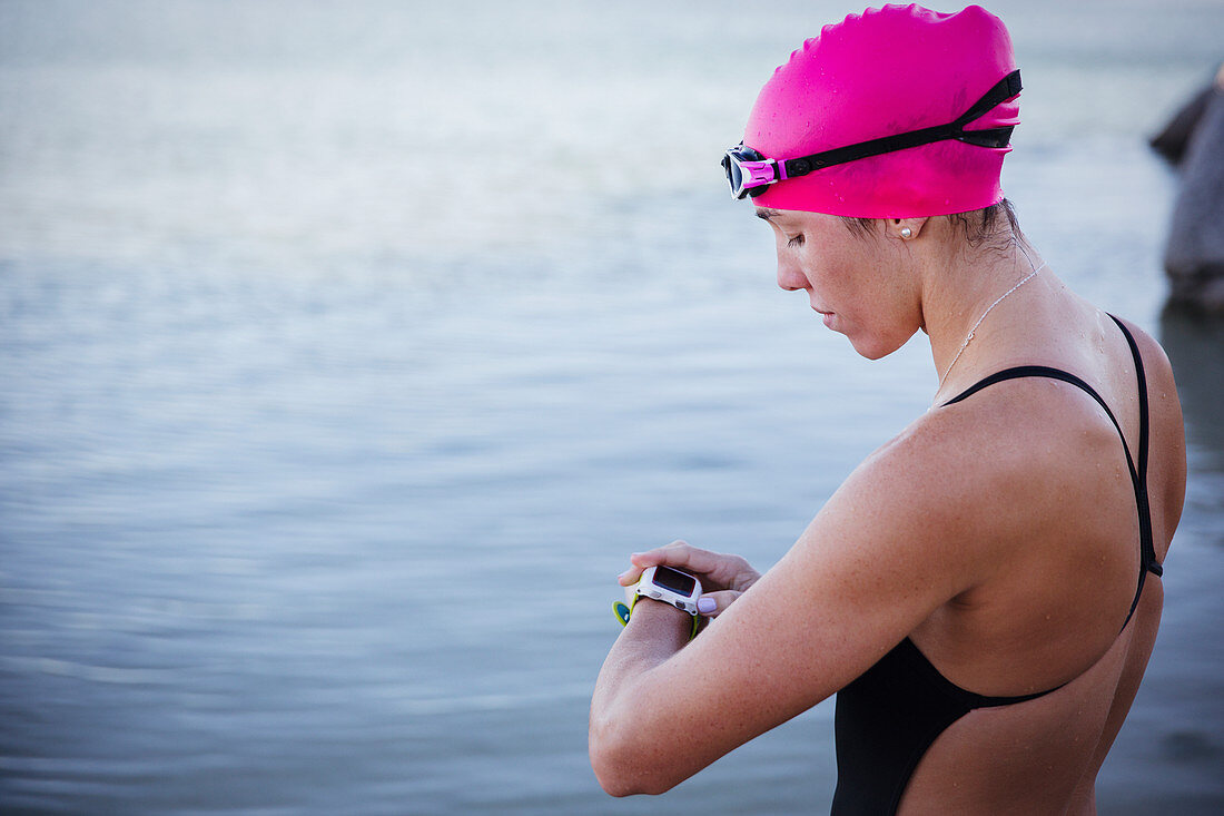 Female swimmer checking smart watch at ocean