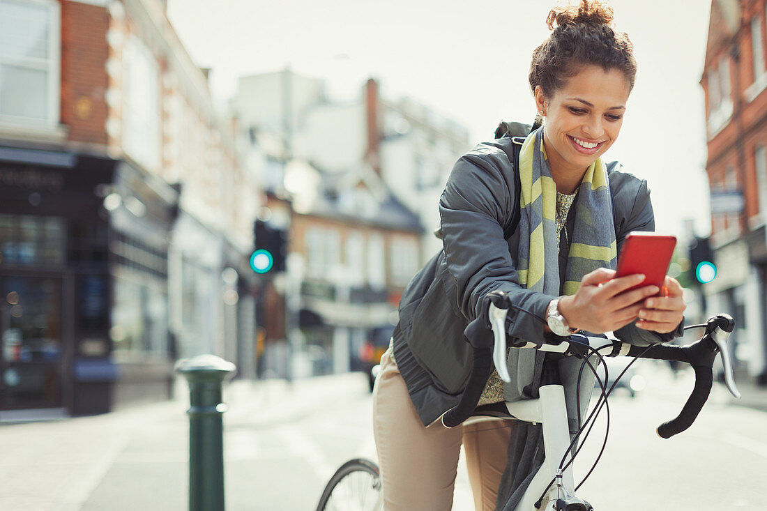 Smiling woman commuting with bicycle, texting
