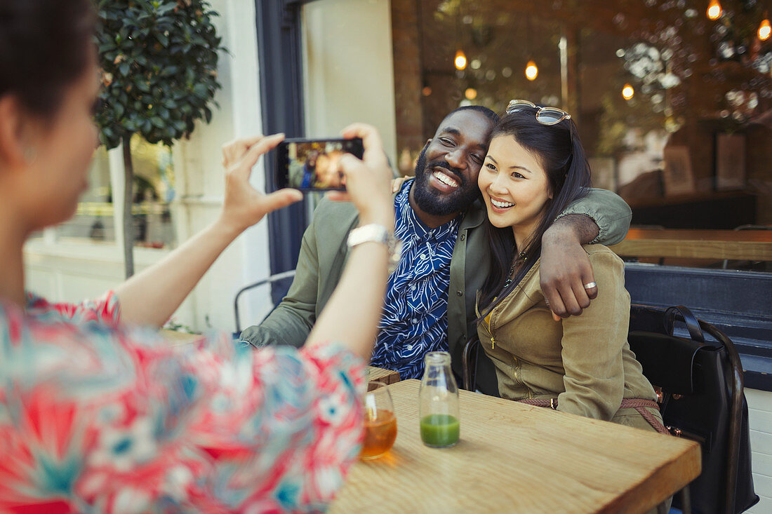 Woman photographing affectionate couple friends